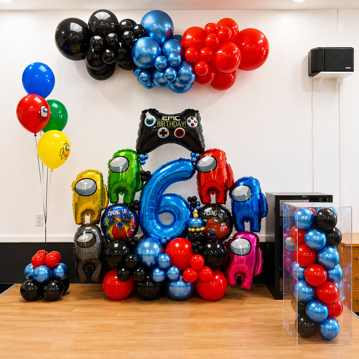Among Us themed 6th birthday balloon display featuring colorful character balloons, a large blue number 6, black, blue, and red balloon clusters, gaming controller decor, and matching party balloons.