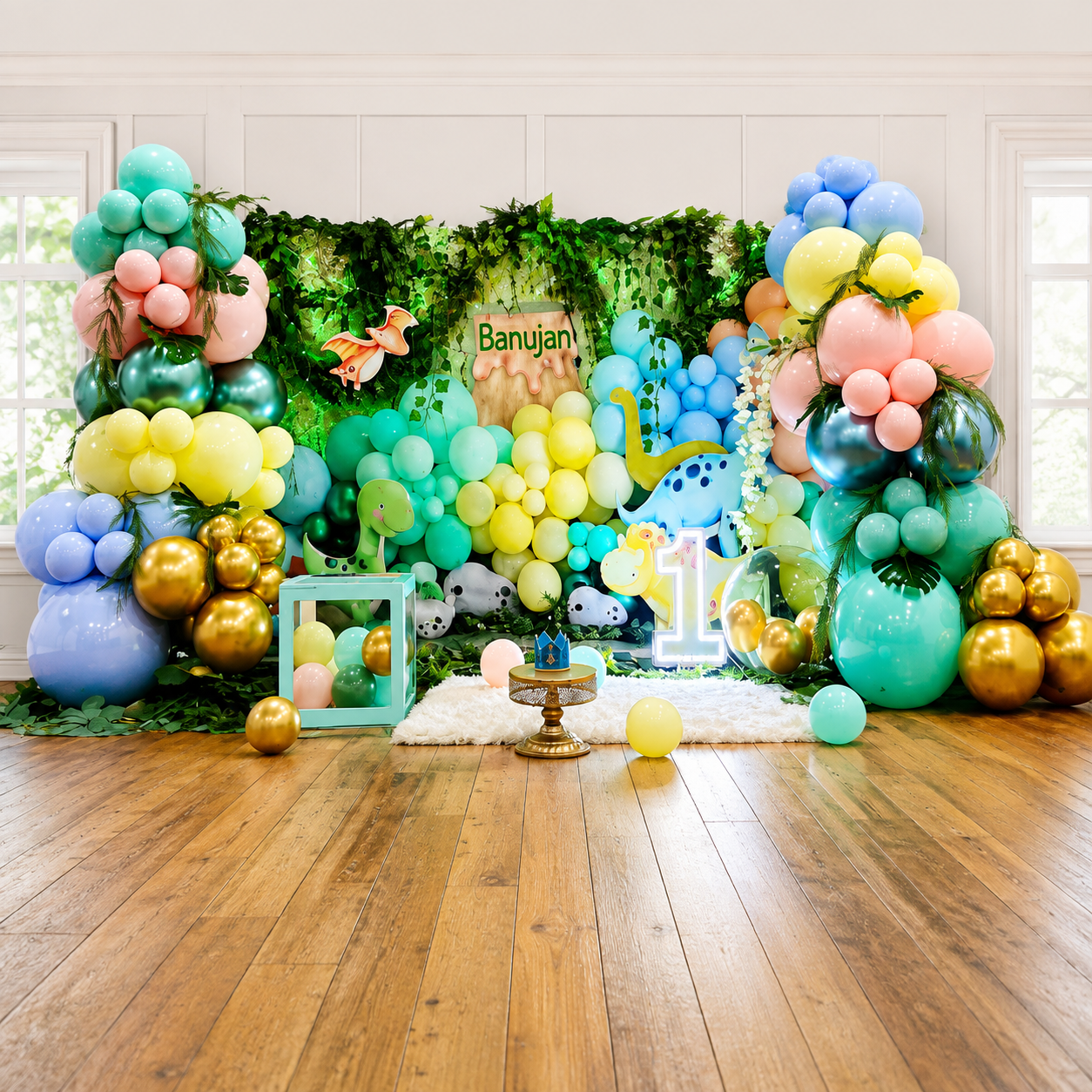 Banujan’s first birthday dinosaur backdrop featuring colorful pastel balloon garlands, greenery, dinosaur cutouts, gold accents, a large number 1, and a jungle-themed display.