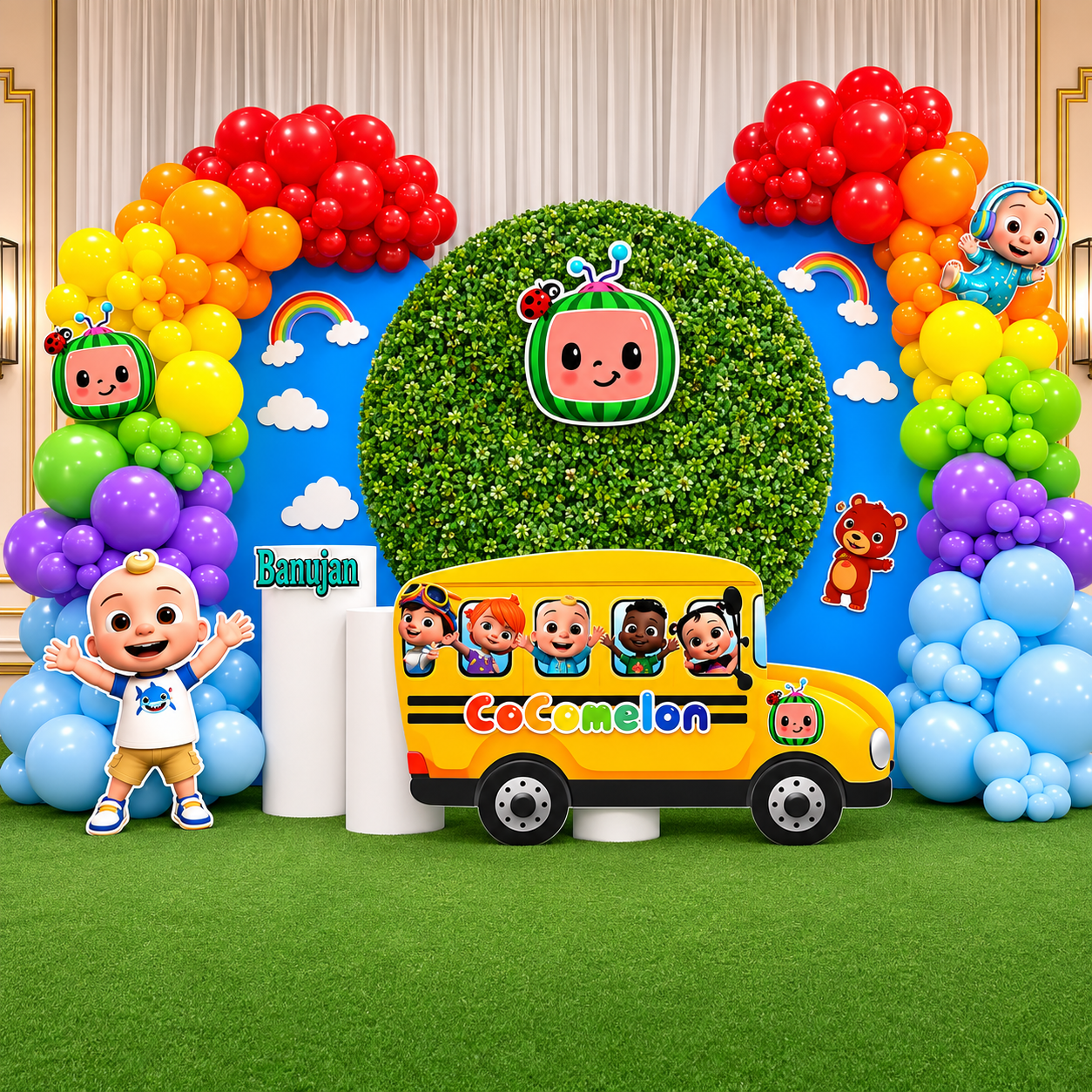 Colorful Cocomelon birthday backdrop featuring rainbow balloon garlands, character cutouts, a yellow school bus display, greenery wall, clouds, and bright party decor.