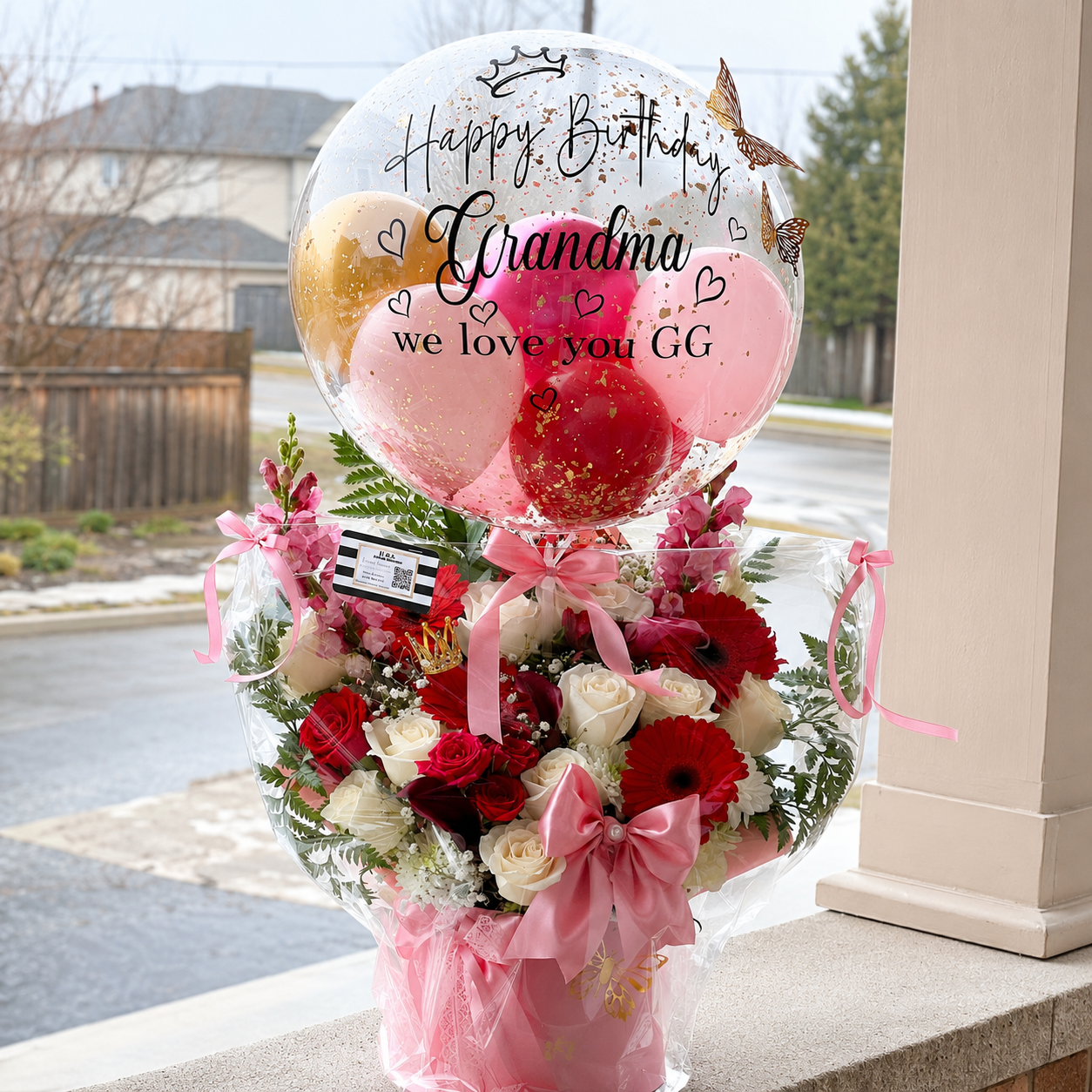 Birthday gift for Grandma featuring a personalised clear balloon, red and pink balloons, red and white flowers, butterflies, and pink ribbon accents.