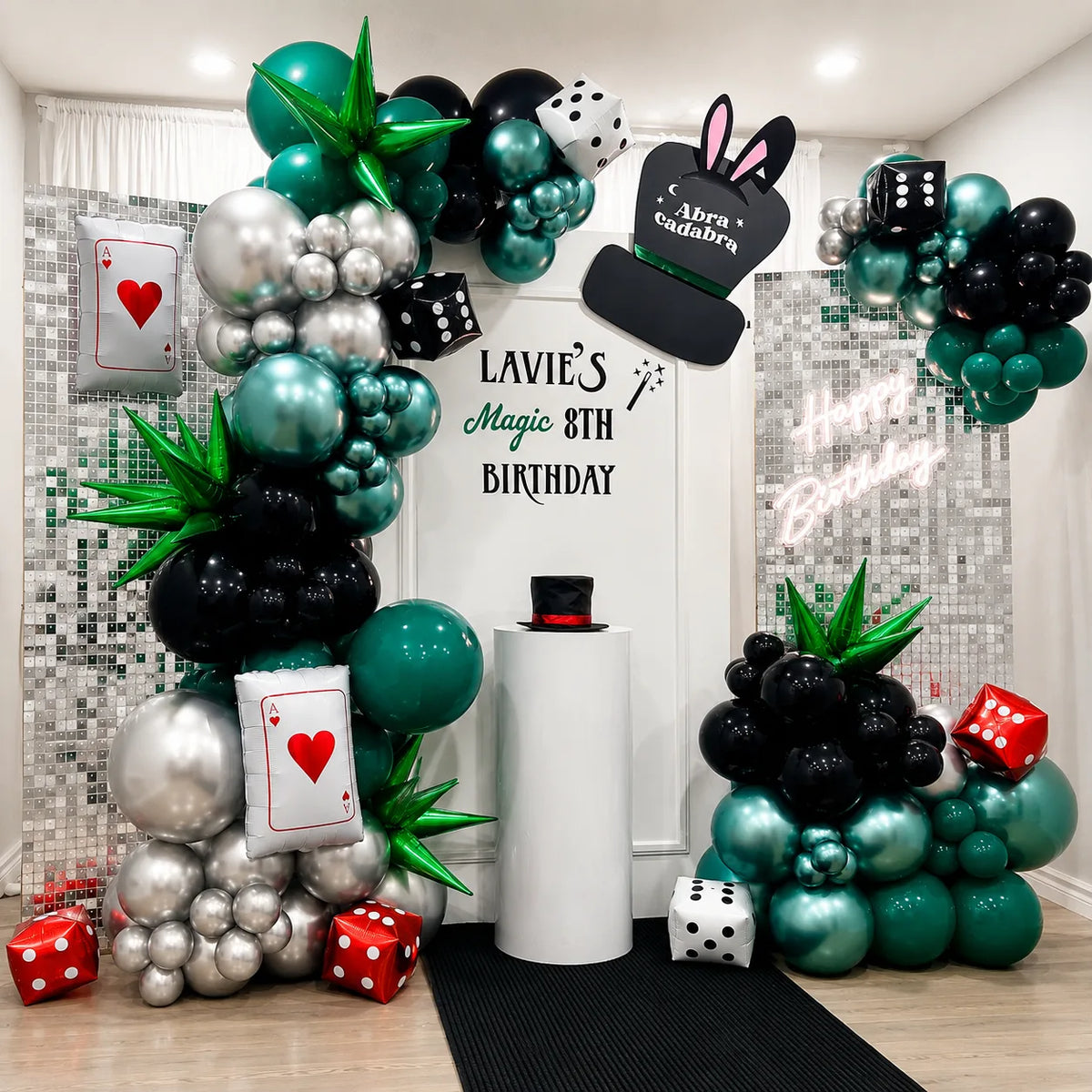 Lavie’s 8th birthday magic-themed backdrop featuring green, black, and silver balloons, playing cards, dice, a magician hat, and shimmer panels.