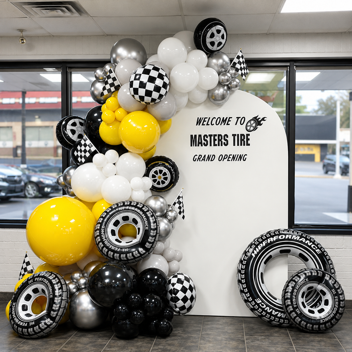 Masters Tire grand opening display featuring black, white, silver, and yellow balloons with tyre-shaped balloons and racing flags.
