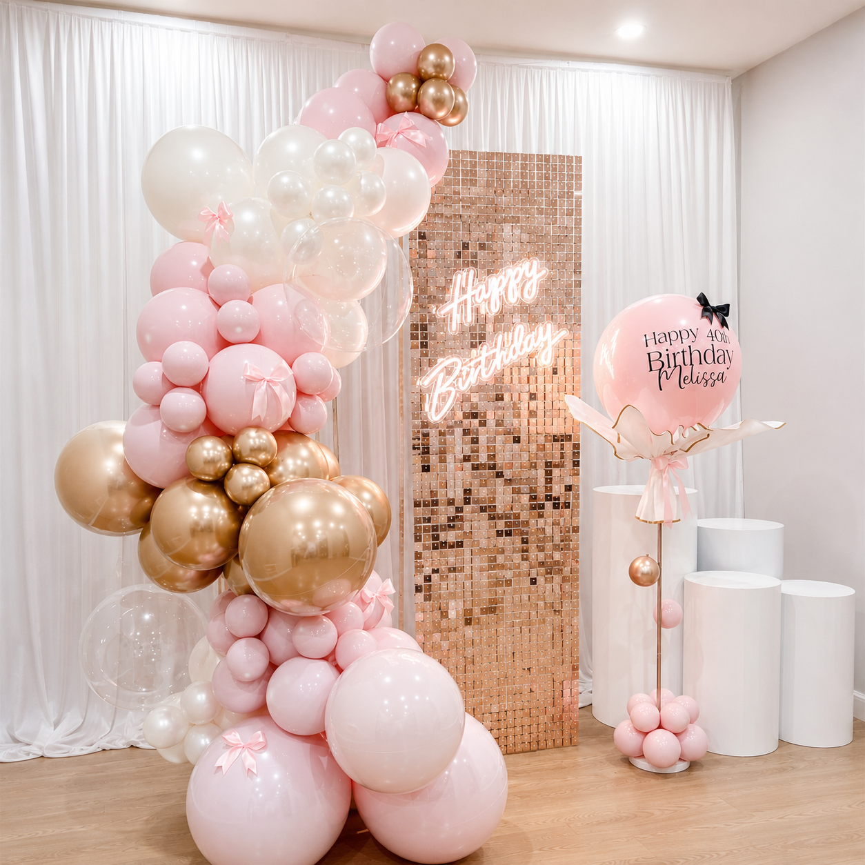 Melissa’s 40th birthday backdrop featuring blush pink, white, and champagne gold balloons, a rose gold shimmer panel with Happy Birthday neon sign, personalized pink balloon, and white pedestal stands.