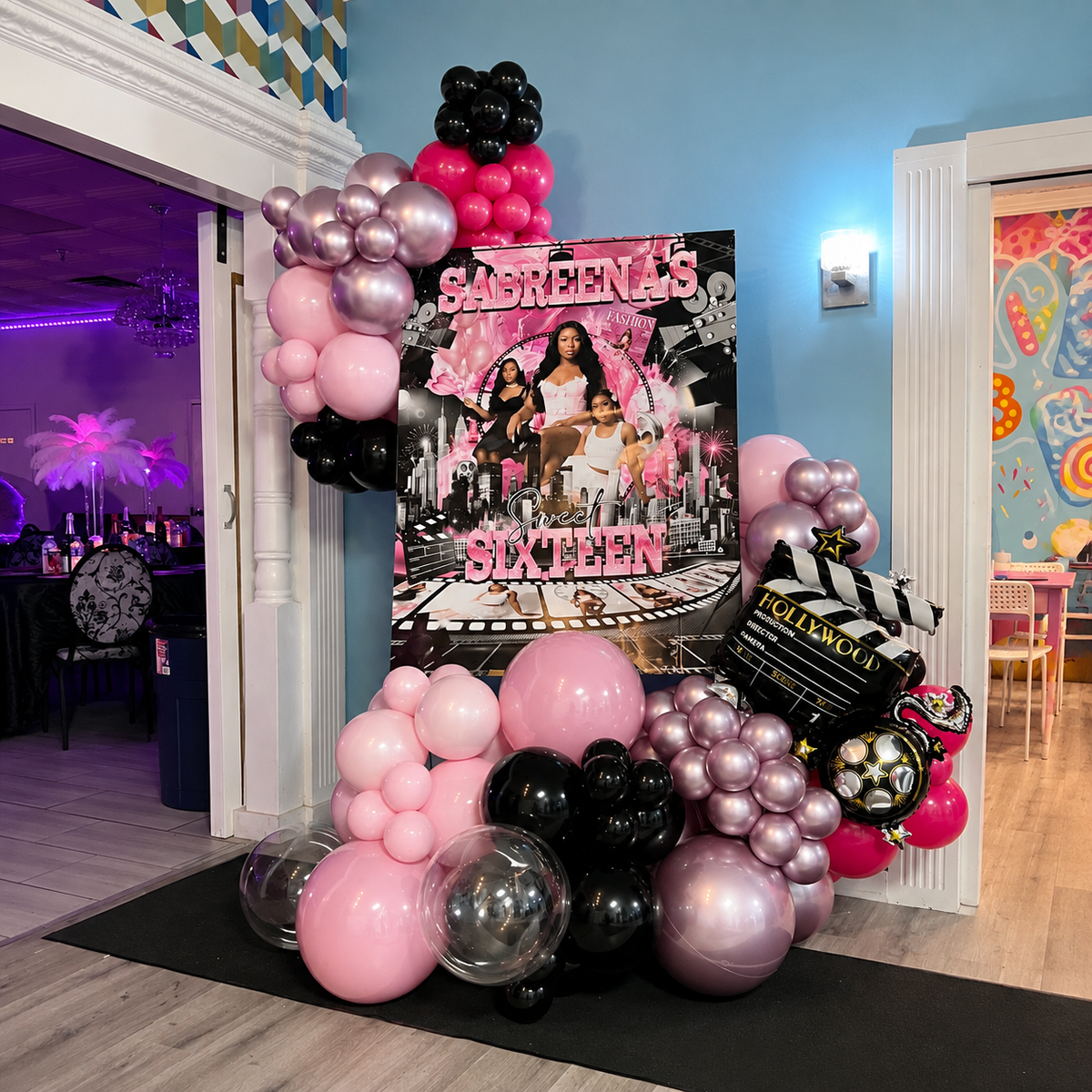 Sabreena’s Sweet Sixteen Hollywood-themed photo display featuring a personalised poster, pink, black, and silver balloon garland, and movie clapboard decorations.
