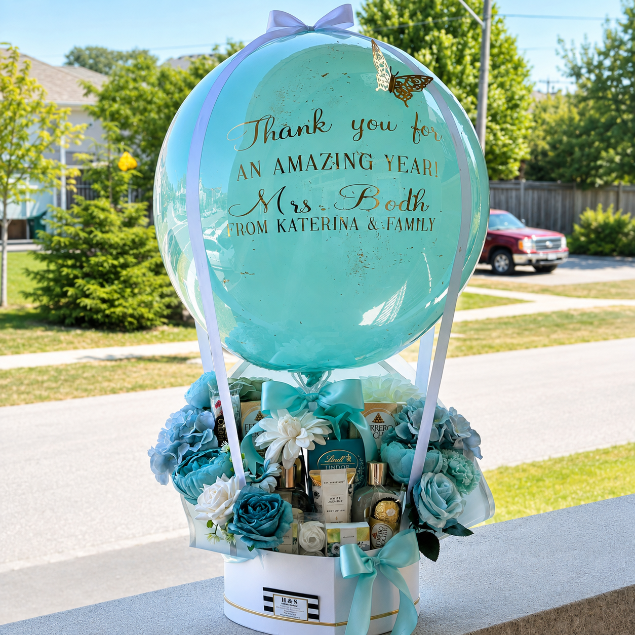 Teacher appreciation gift for Mrs. Bodh featuring a personalised aqua balloon, blue and white flowers, chocolates, beauty products, and turquoise ribbon accents.
