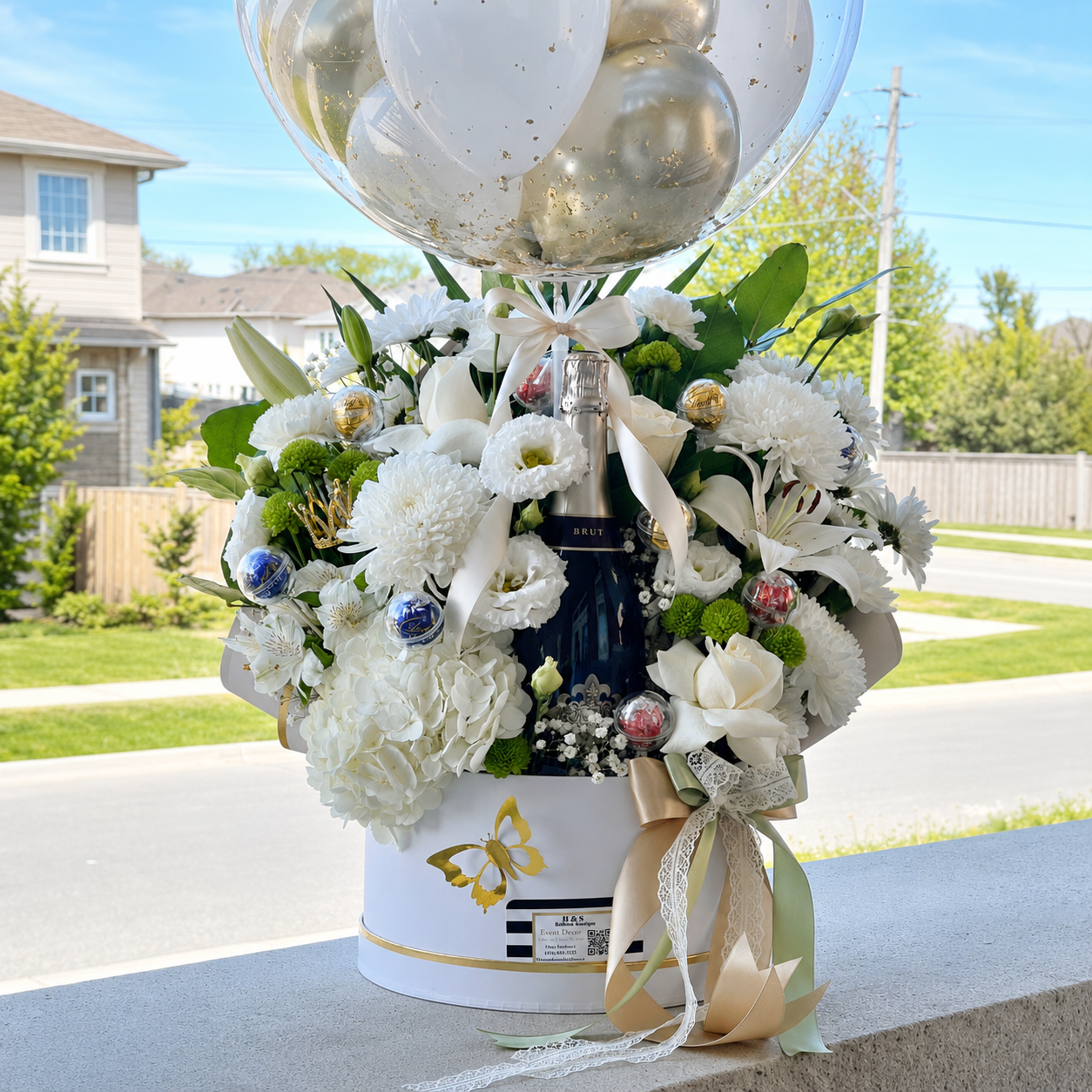 Luxury 50th birthday gift for Maria featuring a personalised clear balloon, white and gold balloons, fresh flowers, and a champagne bottle.